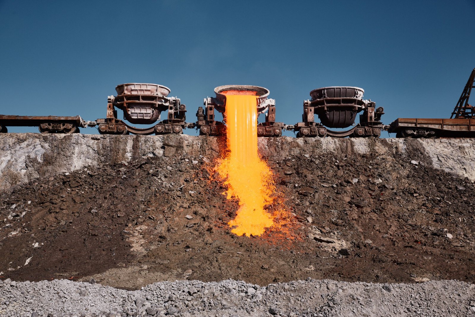 The molten slag is poured from a crucible mounted on a railway platform. A stream of molten slag.