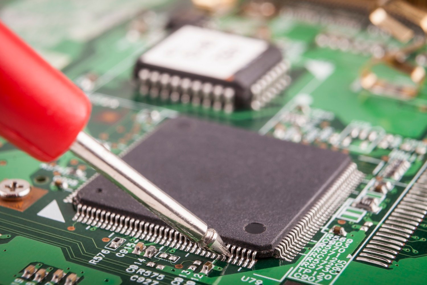 Measuring micro chip with red probe on green circuit board